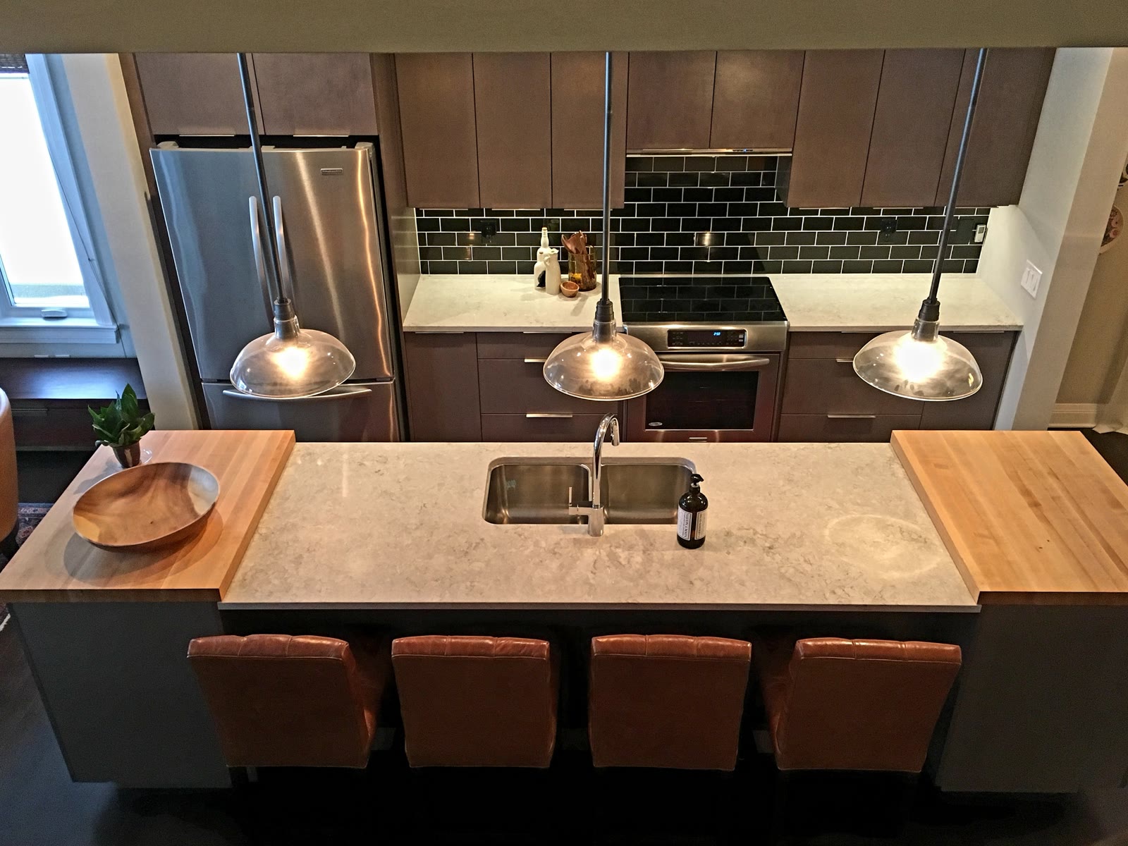 Modern kitchen with dark custom cabinets, a stone island and pendant lights